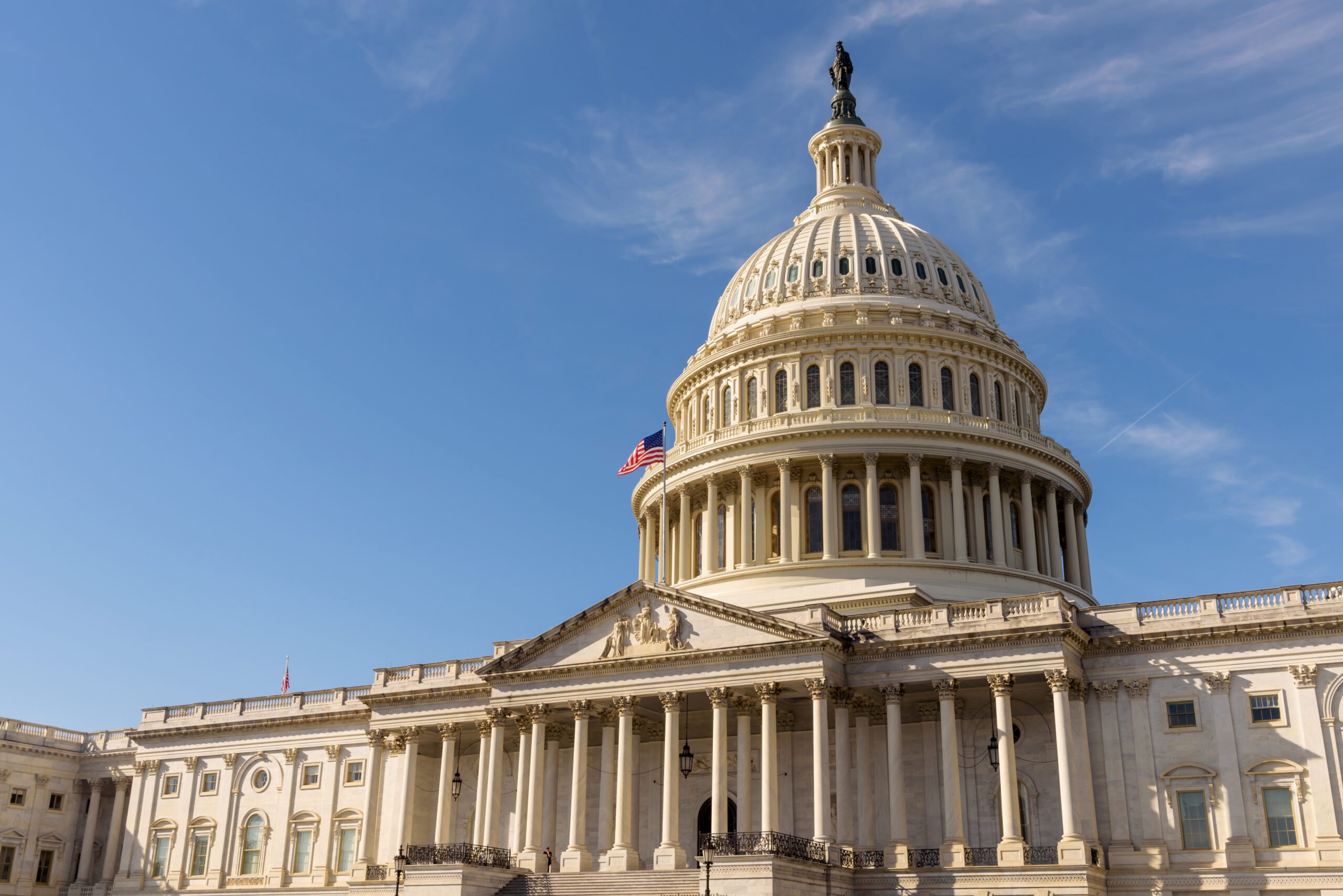 The United States Capitol building with the American flag flying atop its flagpole, Washington DC The U.S. Capitol Building in Washington, D.C., with a clear blue sky and American flag, representing the federal fiscal year-end and government contracting opportunities.