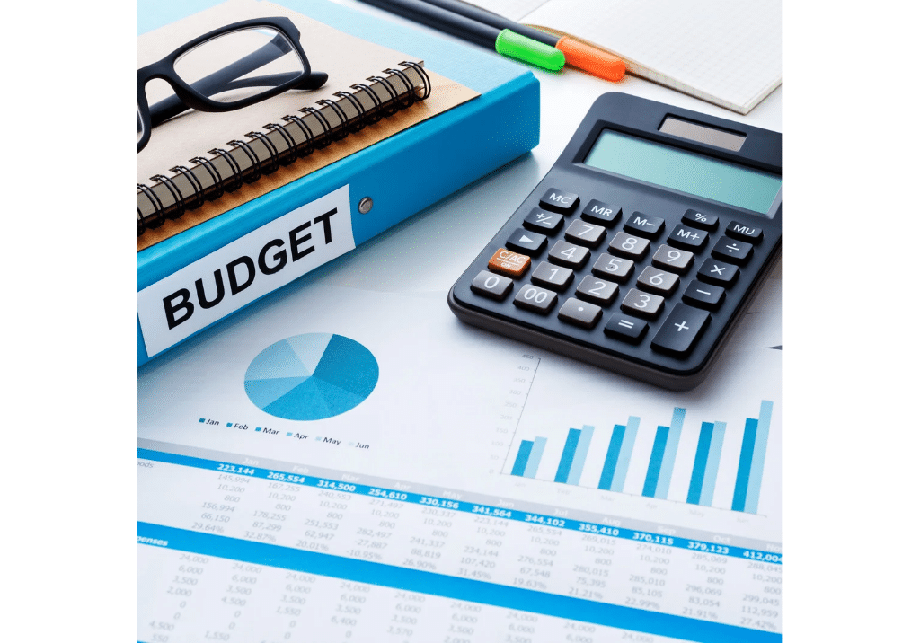 Budget planning documents, financial charts, calculator, and binder used for government contractor budgeting and forecasting