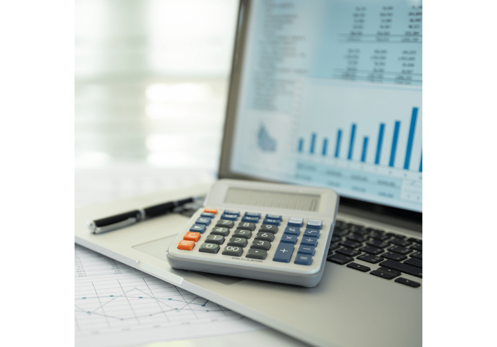 Laptop displaying financial charts and reports beside a calculator, representing mid-year financial review and planning before Q4